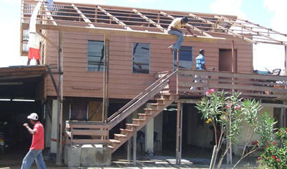 Het dak van Bhaiko Badrie wordt hersteld. Hij is blij met de hulp van de overheid. 