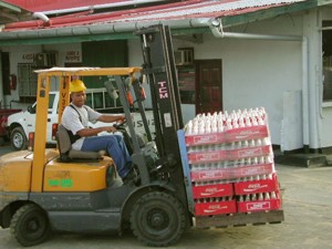 Foto:dWT foto / Beta DebidienOnderschrift:Een lifttruckchauffeur verplaatst een pallet met softflessen op het complex van de Fernandes Bottling Company te Nickerie. Fernandes sluit deze afdeling per eind mei uit efficiency-overwegingen.-. 