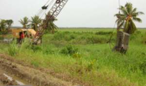 Foto: Een dragline bezig met het uitdiepen van de hoofdlozing in de Middenstandspolder in het district Nickerie.-.