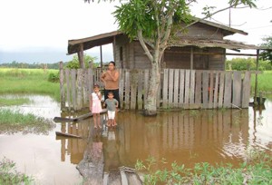 Foto: Mevrouw Premdei Ganga probeert met haar kinderen via een loopplank op de weg te komen.-.