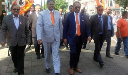 Vanuit het kantoor van ondernemer Robbie Bhoendie aan de Beeklaan is Santokhi onderbegeleiding van een Tazza-groep gelopen naar de Weimarstraat voor de opening van het VHP-infocentrum. 